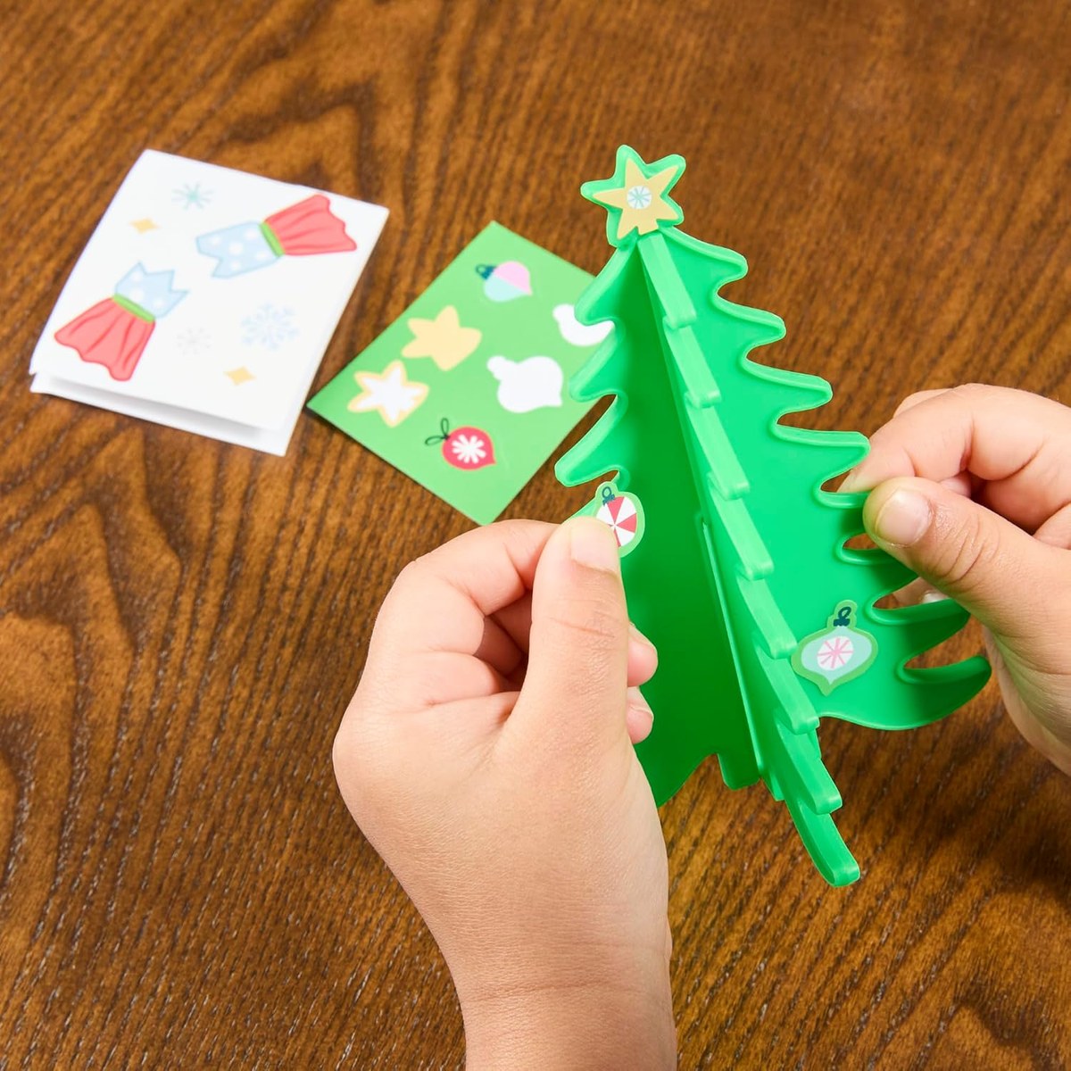 Child holding the paper Christmas tree and sticker sheets